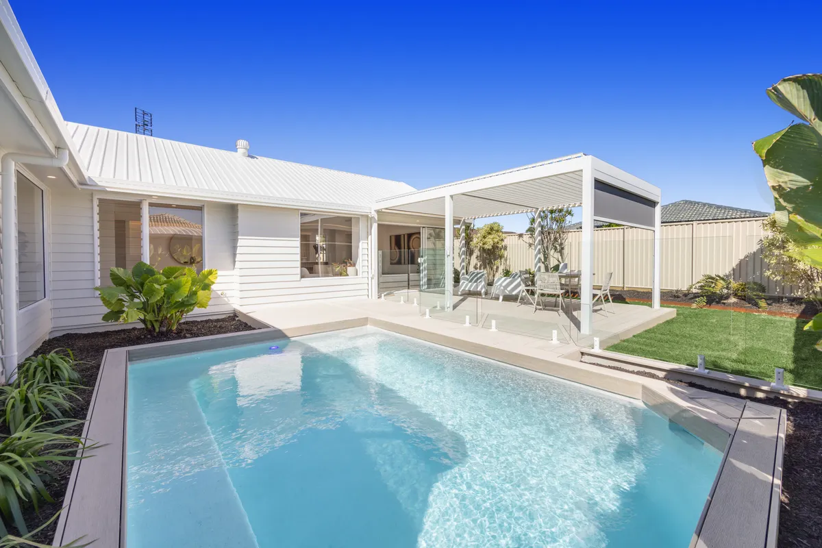 Minyama House pool with pale coping, glass fencing and a covered outdoor living area
